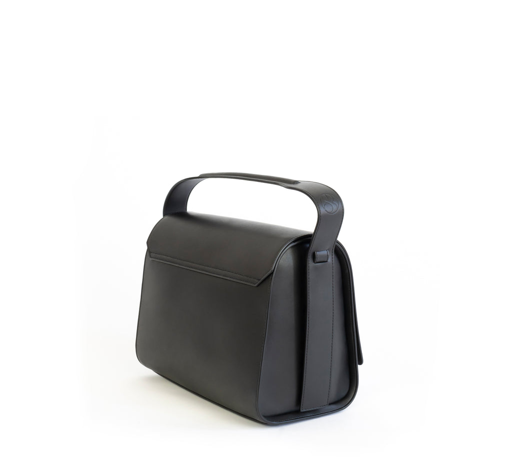 Black eco vegan leather barrel shoulder bag by Sydney Brown. Timeless, classic and modern. Angle back