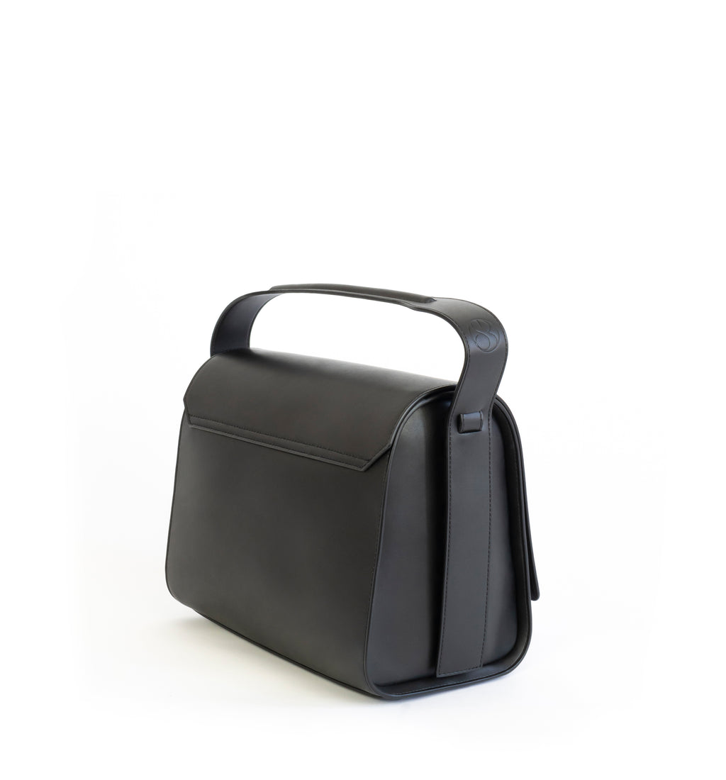Black eco vegan leather barrel shoulder bag by Sydney Brown. Timeless, classic and modern. Angle back
