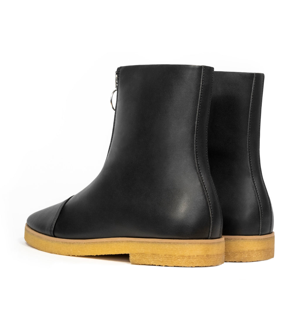 Black vegan leather boot with frontal zip, almond toe, natural rubber crepe sole.