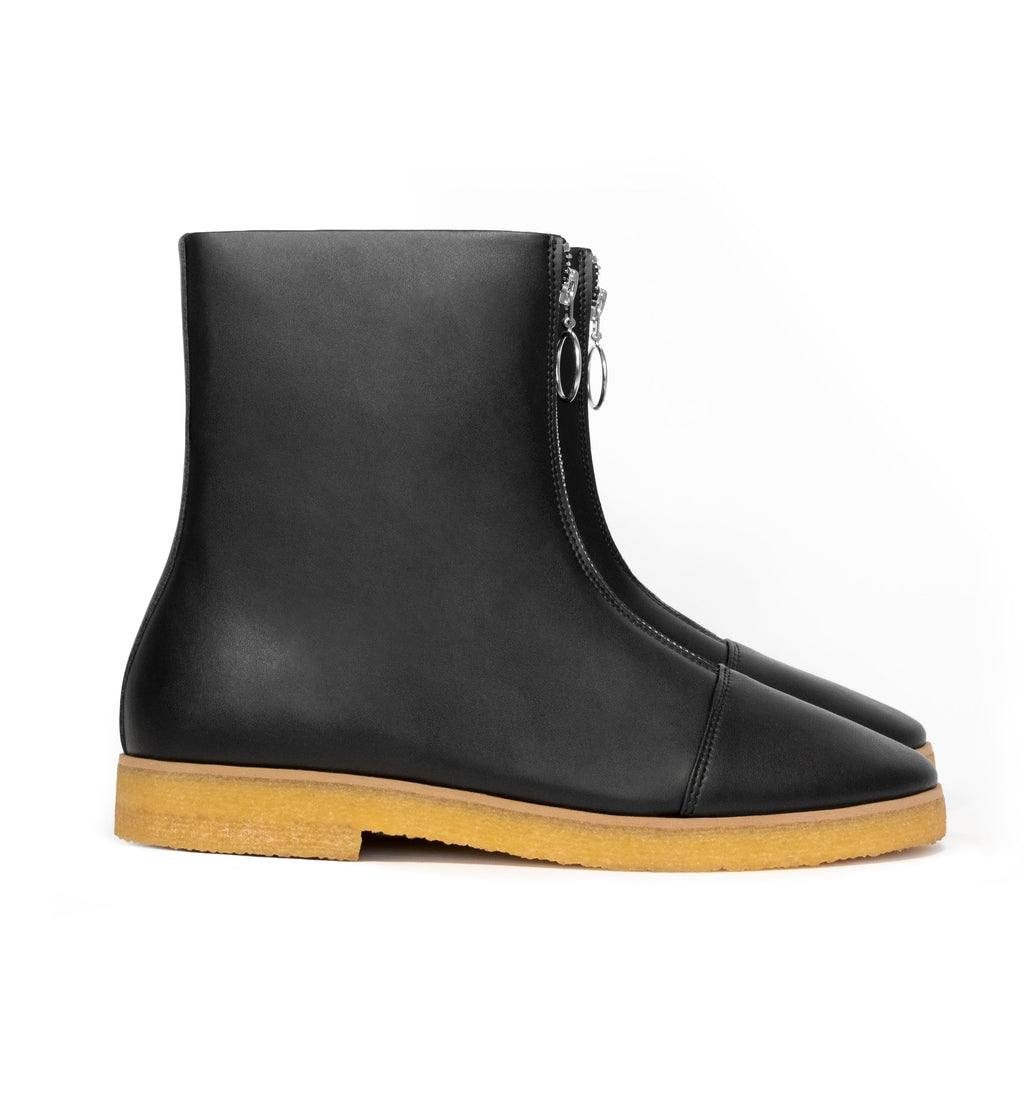 Black vegan leather boot with frontal zip, almond toe, natural rubber crepe sole.