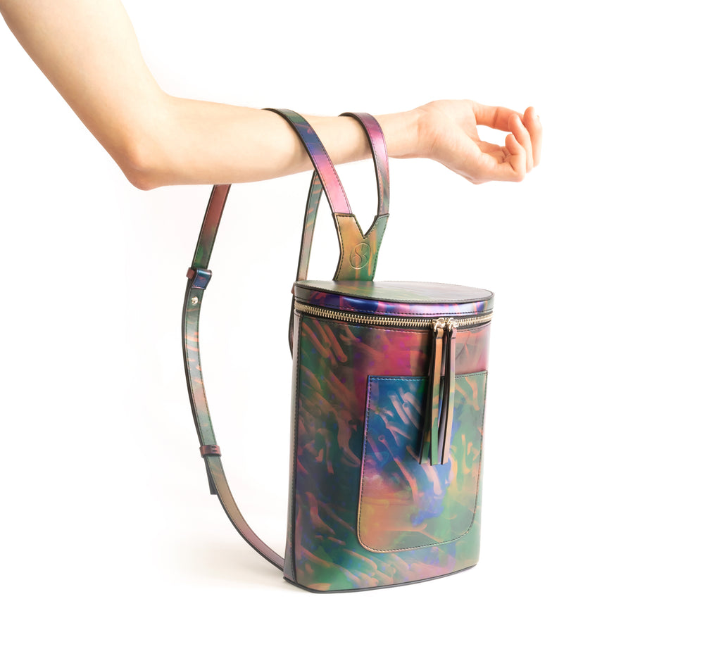 Printed iridescent vegan leather bucket backpack by Sydney Brown. Timeless, classic and modern. Hand View