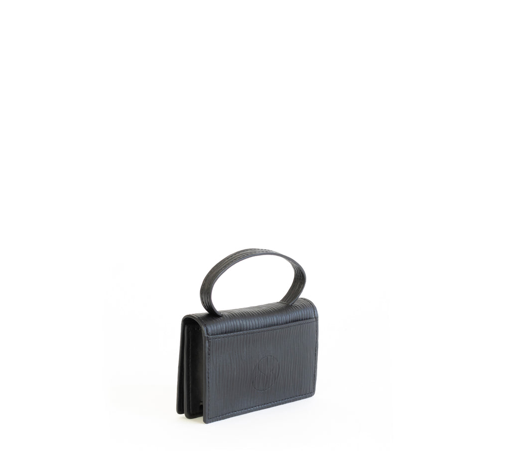 Microbag wallet with handle and an interior and exterior card slot. Black emboss faux-leather. Angle