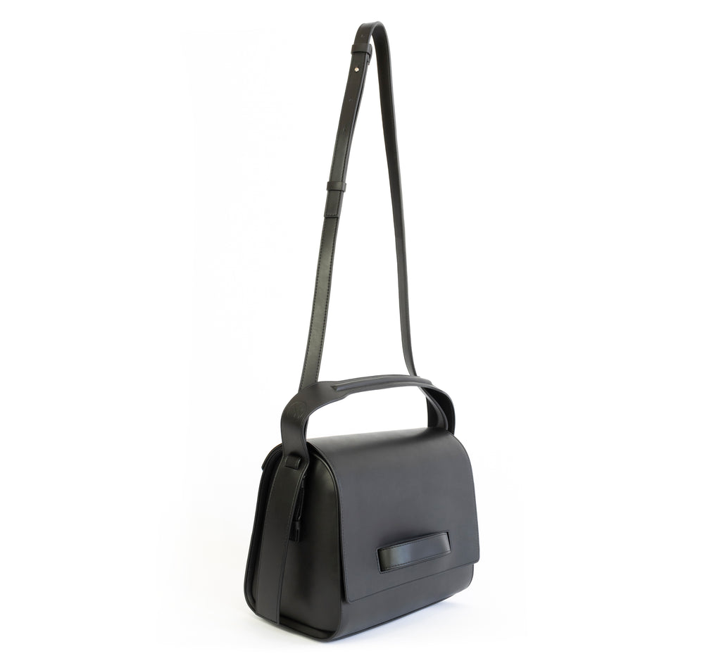 Black eco vegan leather barrel shoulder bag by Sydney Brown. Timeless, classic and modern. Angle Front view shoulder strap