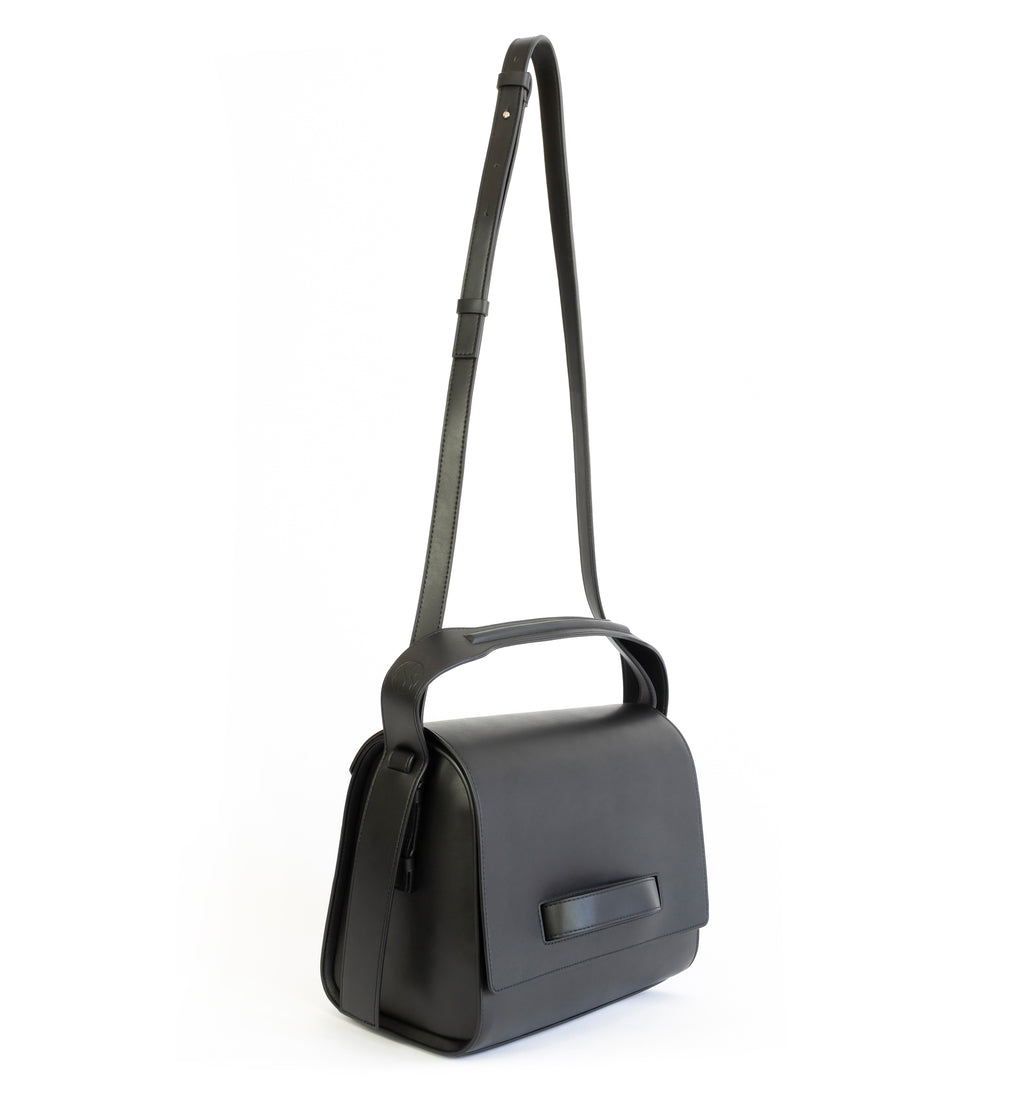 Black eco vegan leather barrel shoulder bag by Sydney Brown. Timeless, classic and modern. Angle Front view shoulder strap