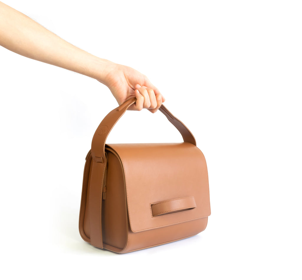 Brown eco vegan leather barrel shoulder bag by Sydney Brown. Timeless, classic and modern. Hand view.