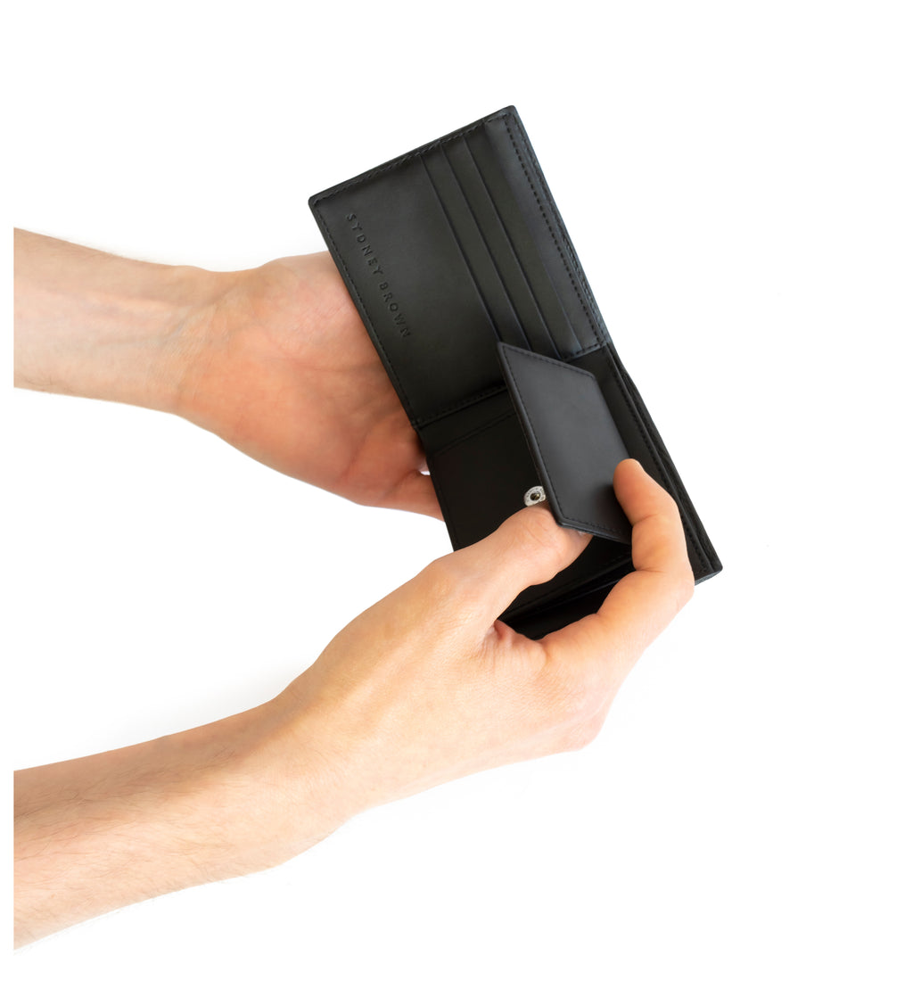 Unisex bifold wallet, practical and timeless. Black Emboss faux-leather. Hand view.