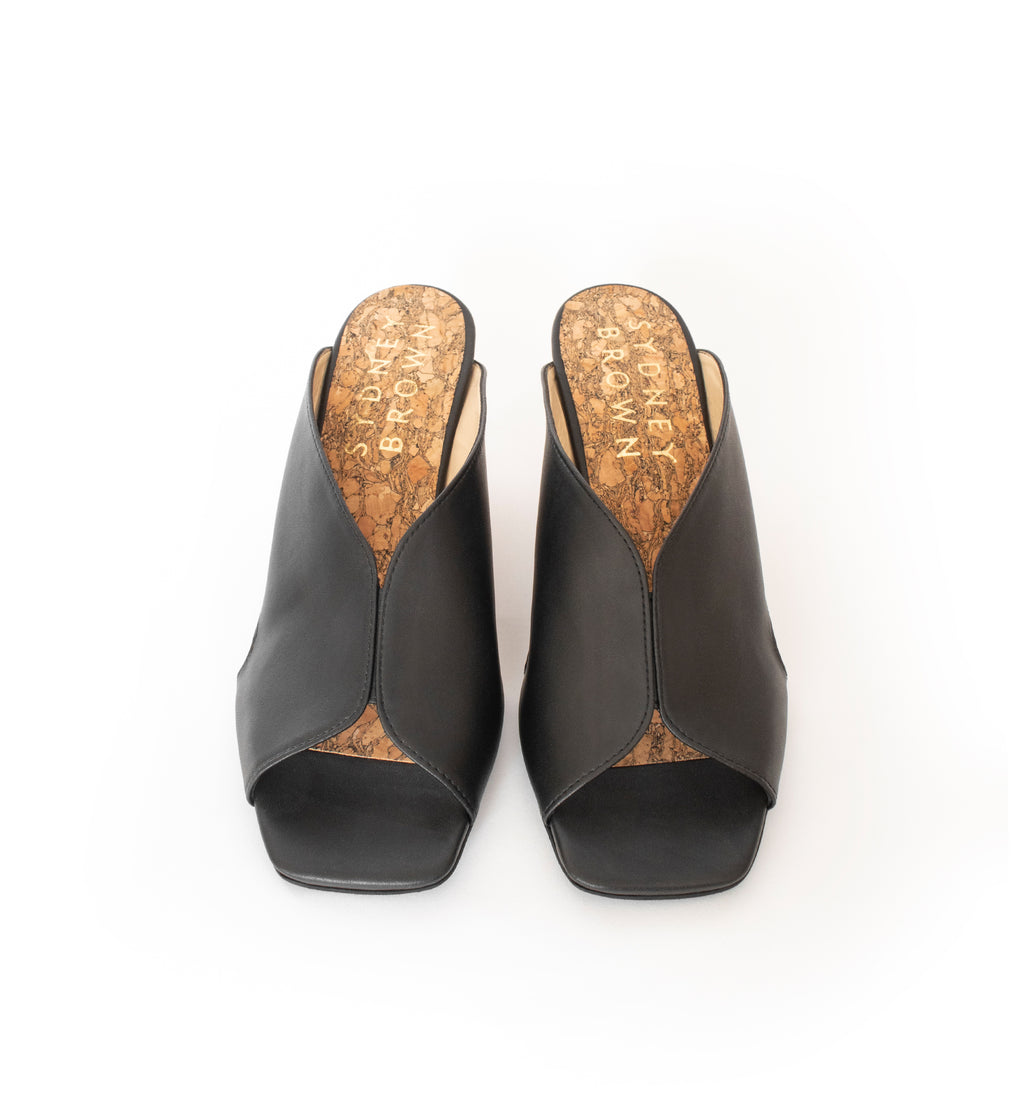 Black faux-leather mule slide with a curved design high heel in light brown wood.