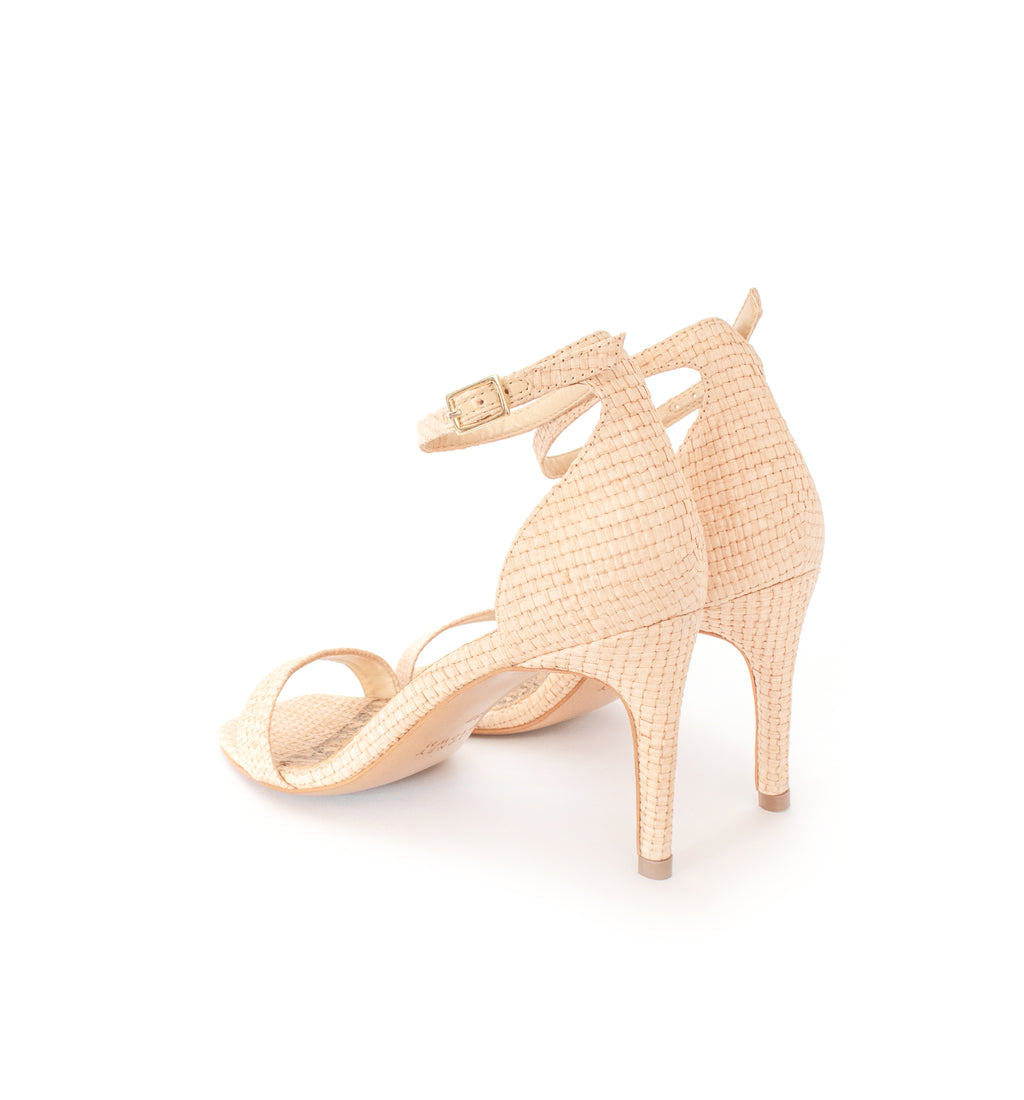 Low Stiletto in natural raffia, ankle strap with metal buckle. Mid-heel in recycled wood pulp, covered with natural raffia.