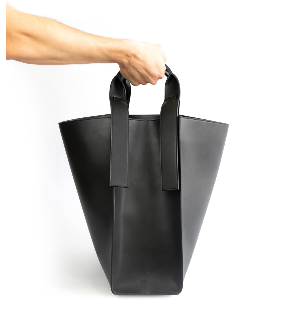 Black eco vegan leather tote shoulder bag by Sydney Brown. Timeless, classic and modern.  Hand view.